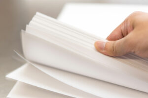 Close-up of a hand holding white paper sheets, representing printing and writing paper quality and smooth handling.