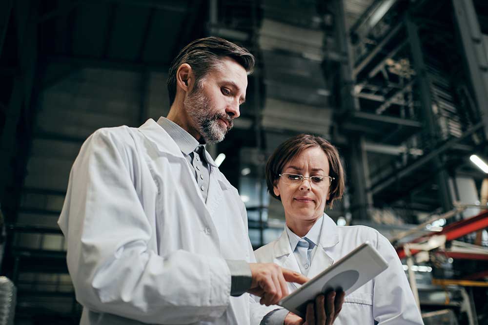Two professionals reviewing documents in a technical environment, representing collaboration and expertise.