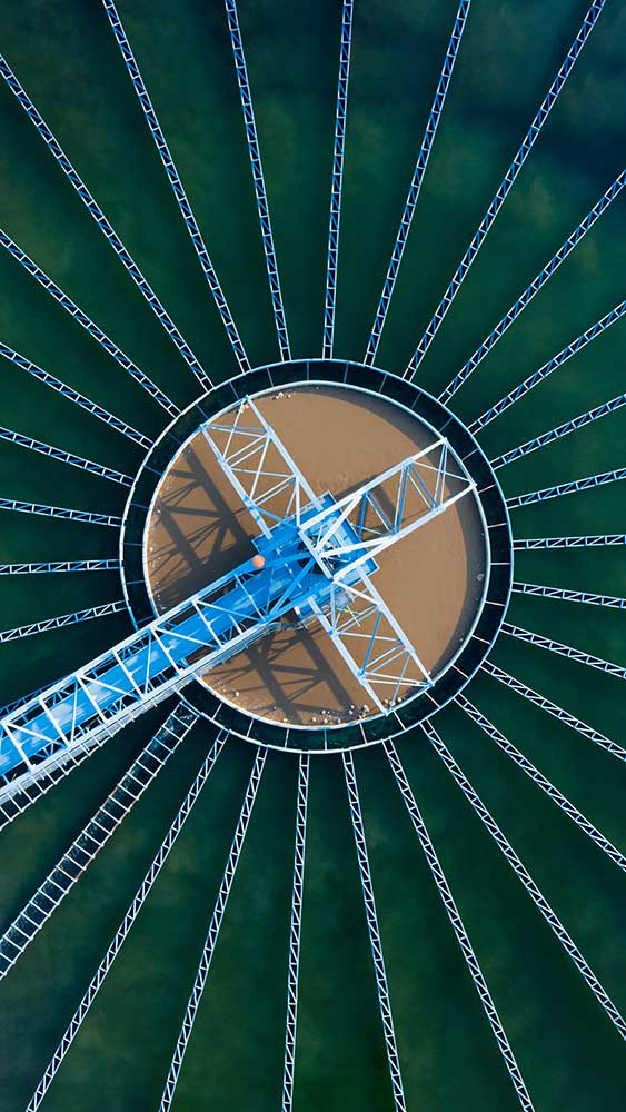 Aerial view of a circular water treatment clarifier, representing process stability and cleaner circuits.