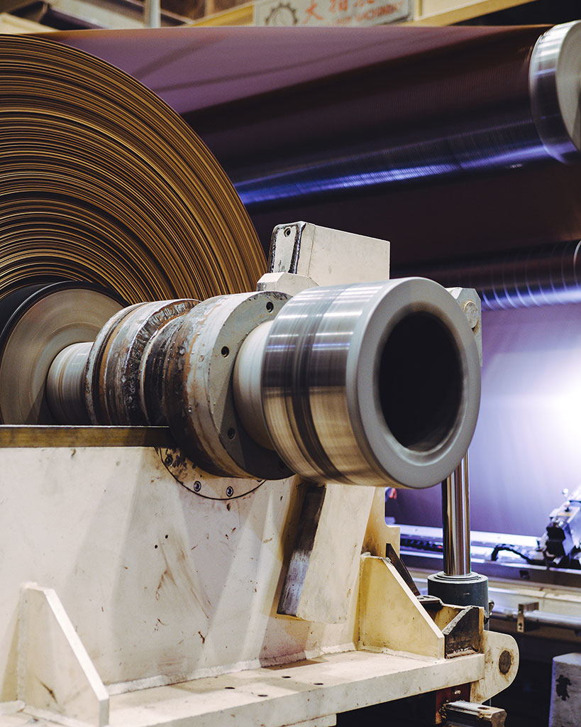 Close-up of a paper reel and machine component, representing wet-end stability and sheet quality control.