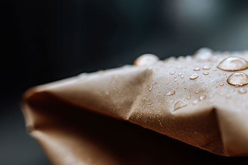 Water droplets on a paper sheet surface, illustrating sizing protection across paper and board applications.